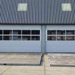 Front view of a modern warehouse building with corrugated roofing and skylights.
